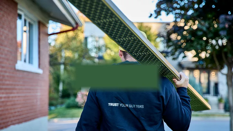Technician carrying a perforated Alu-Rex gutter guard to a residential job